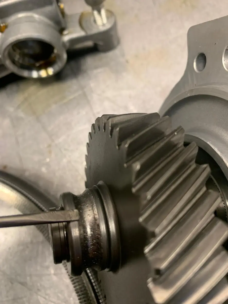 Technician pointing to wear marks on Nissan gearbox gear teeth during diagnostic inspection